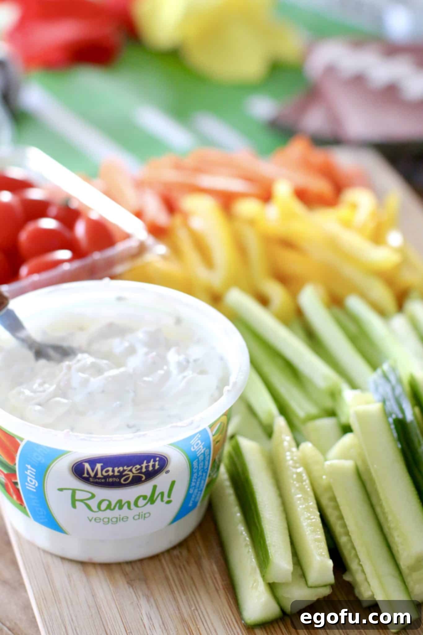 A tray of freshly sliced vegetables next to a tub of ranch dip, ready for assembly.