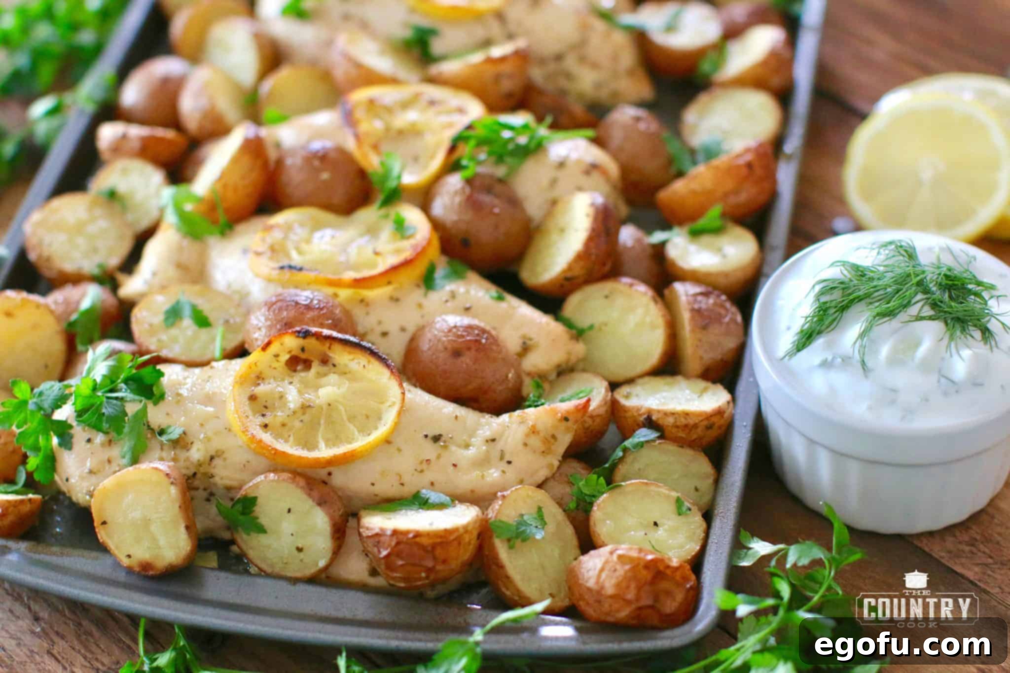 Fully cooked chicken and potatoes on baking sheet and topped with fresh parsley.