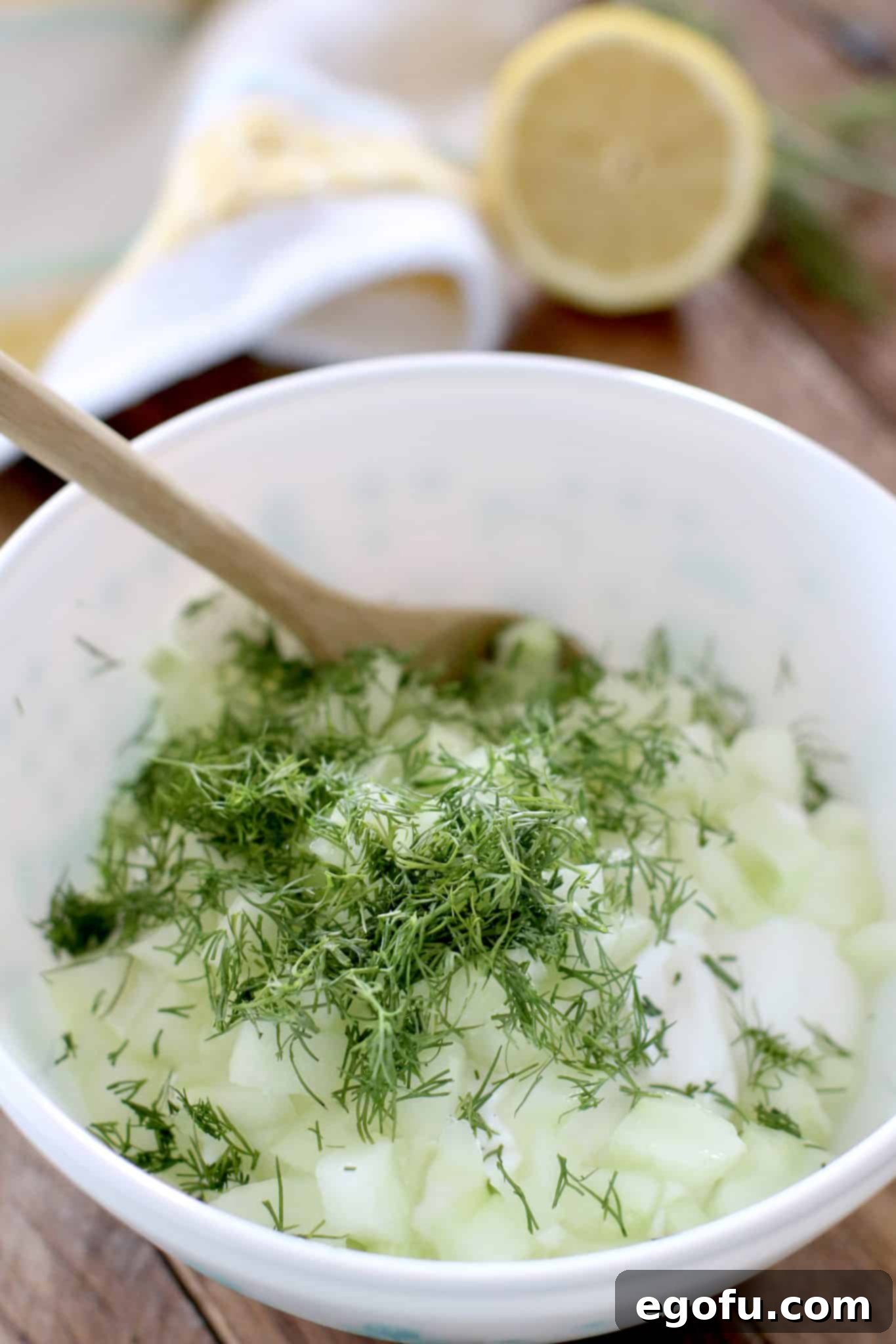 Greek yogurt, dill, cucumber and lemon juice in a white bowl.