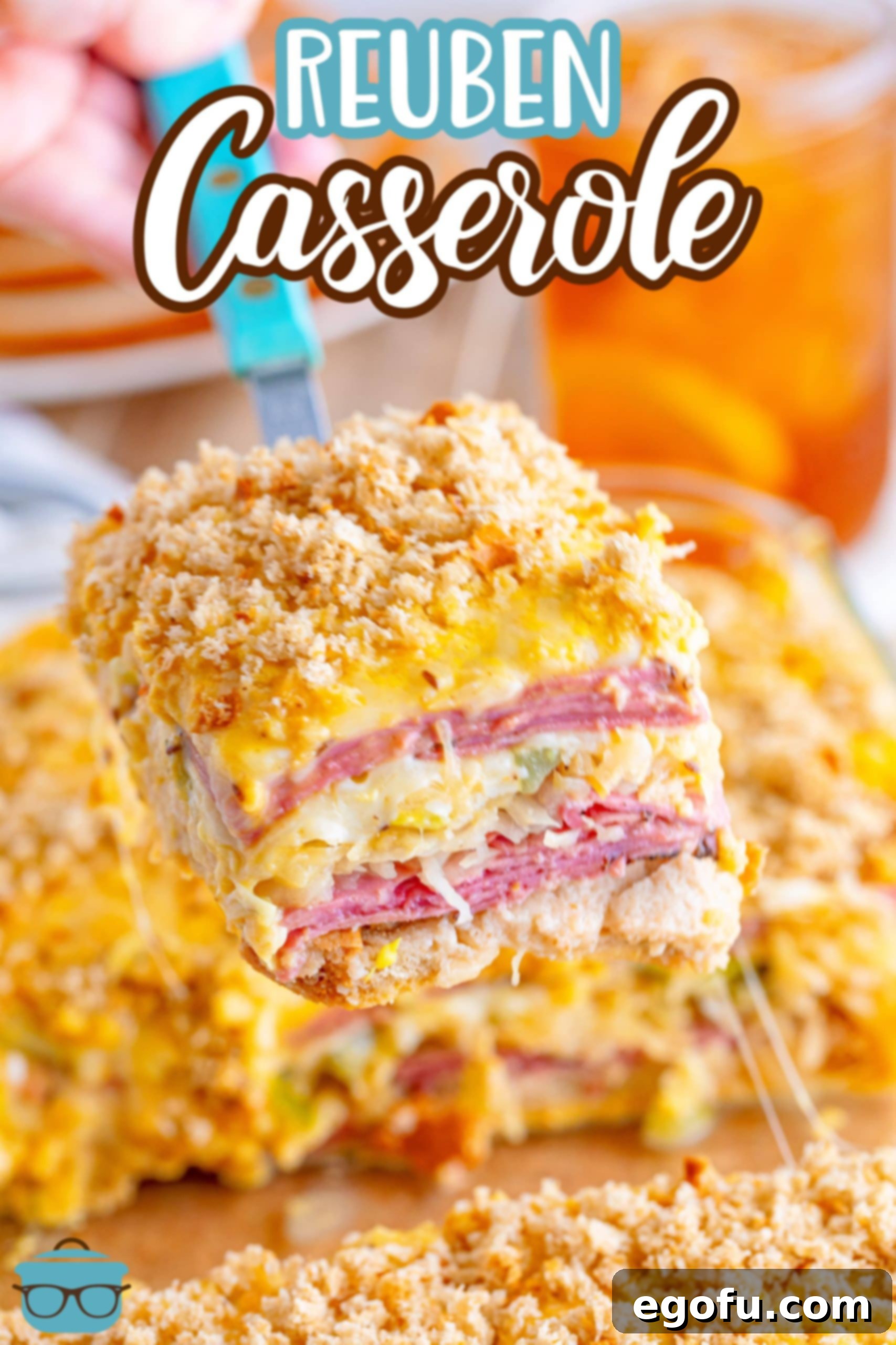 A large baking dish with a serving of Reuben Casserole being held above it.