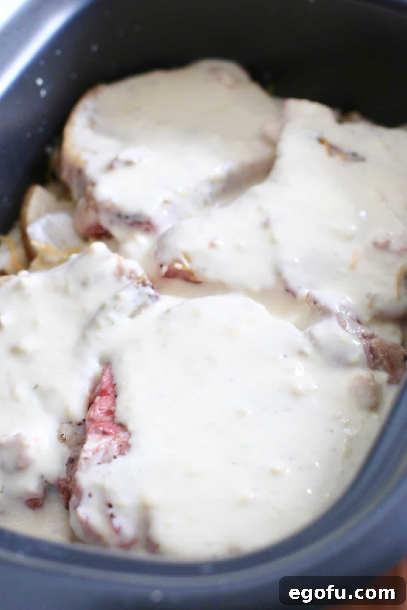 Remaining sauce poured over pork chops in the slow cooker for Smothered Pork Chops