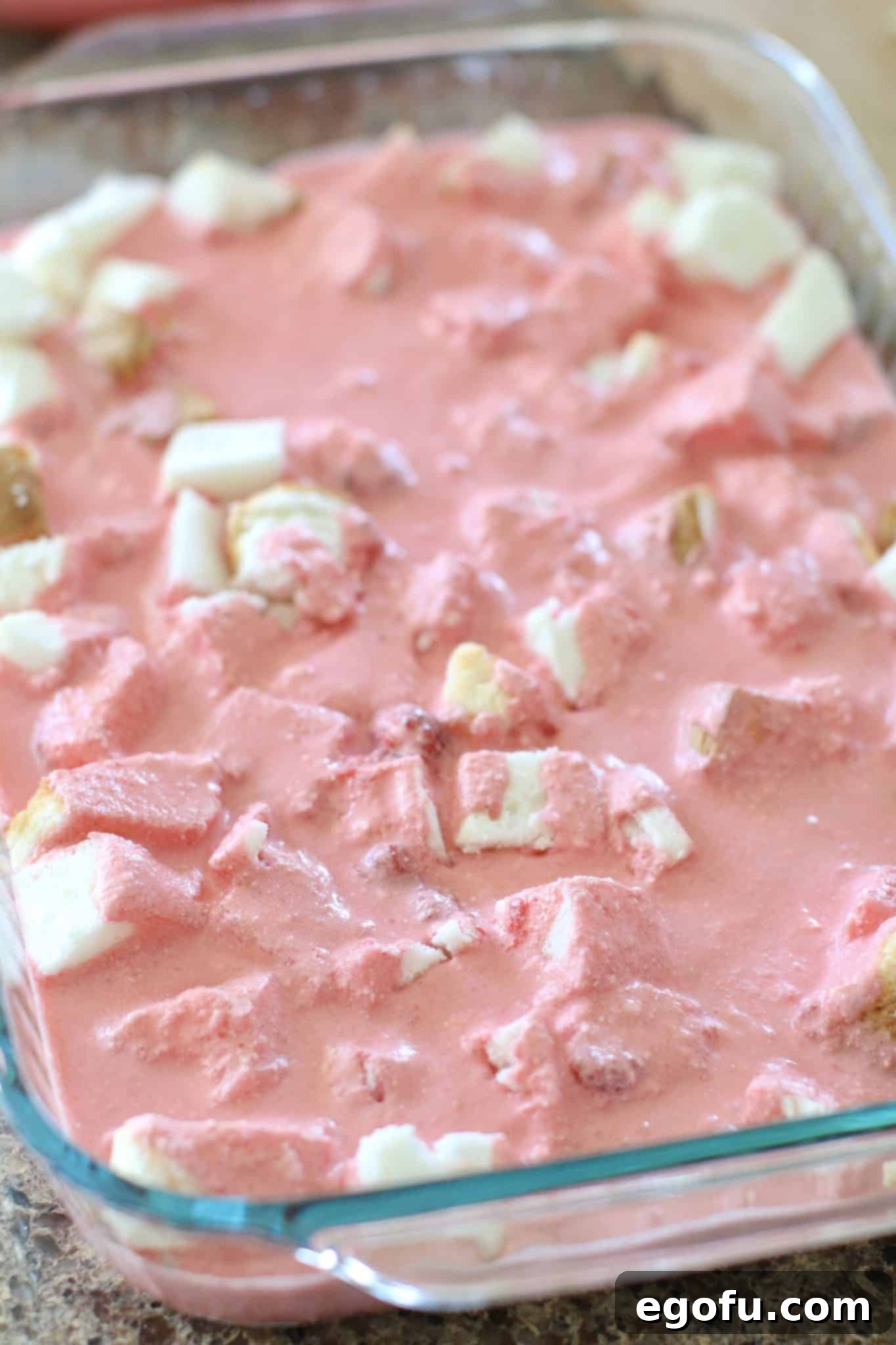 Strawberry Angel Delight 10 Half of the strawberry gelatin and whipped topping mixture spread evenly over the first layer of diced angel food cake in a glass baking dish.