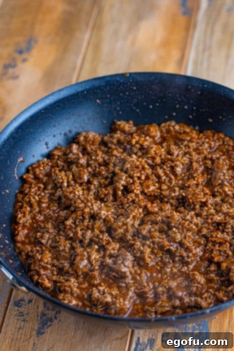 Taco seasoning flavored ground beef simmering in a skillet.