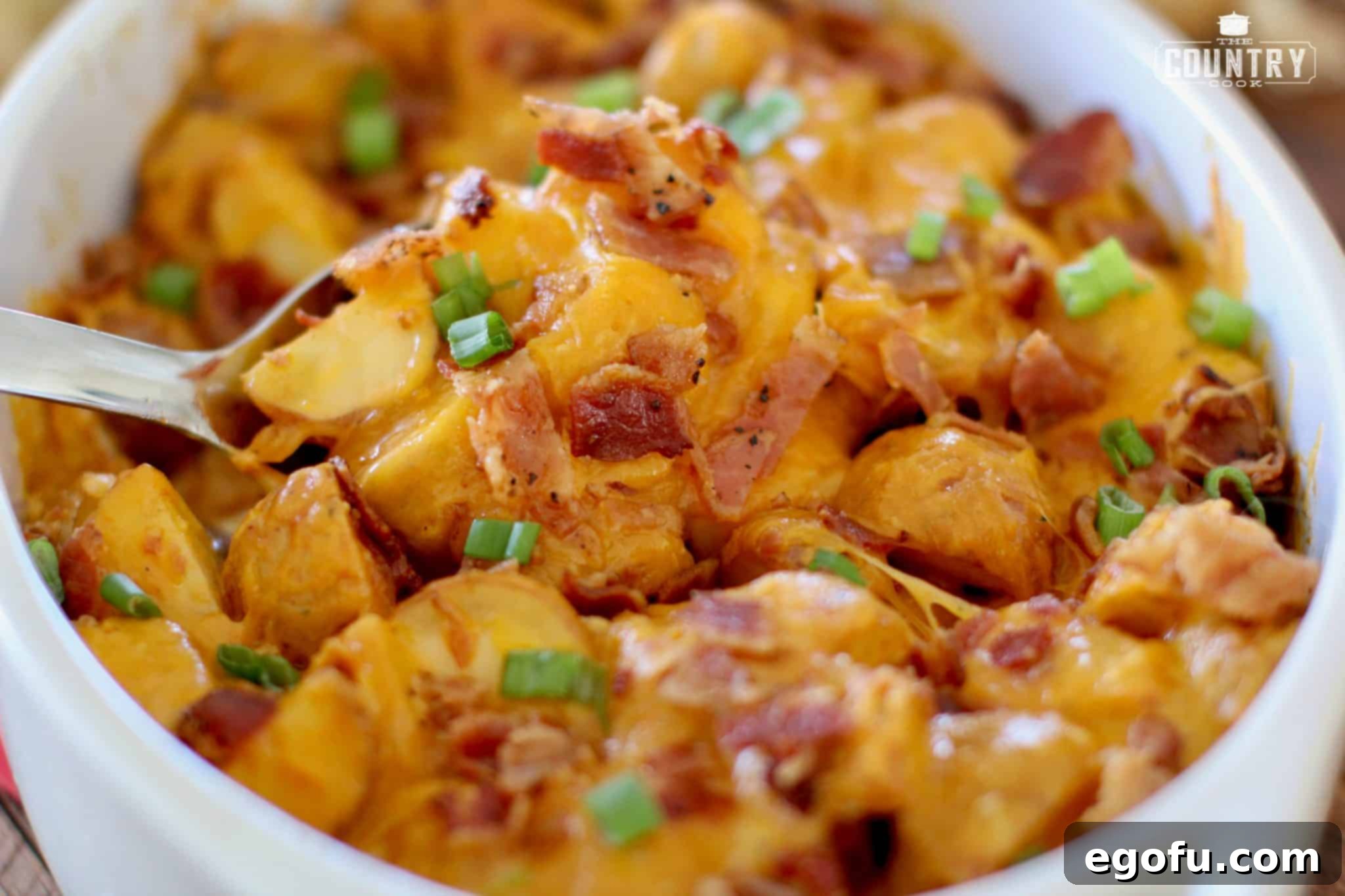 Tex Mex Ranch Potatoes shown in a white oval baking dish with a silver serving spoon inserted.