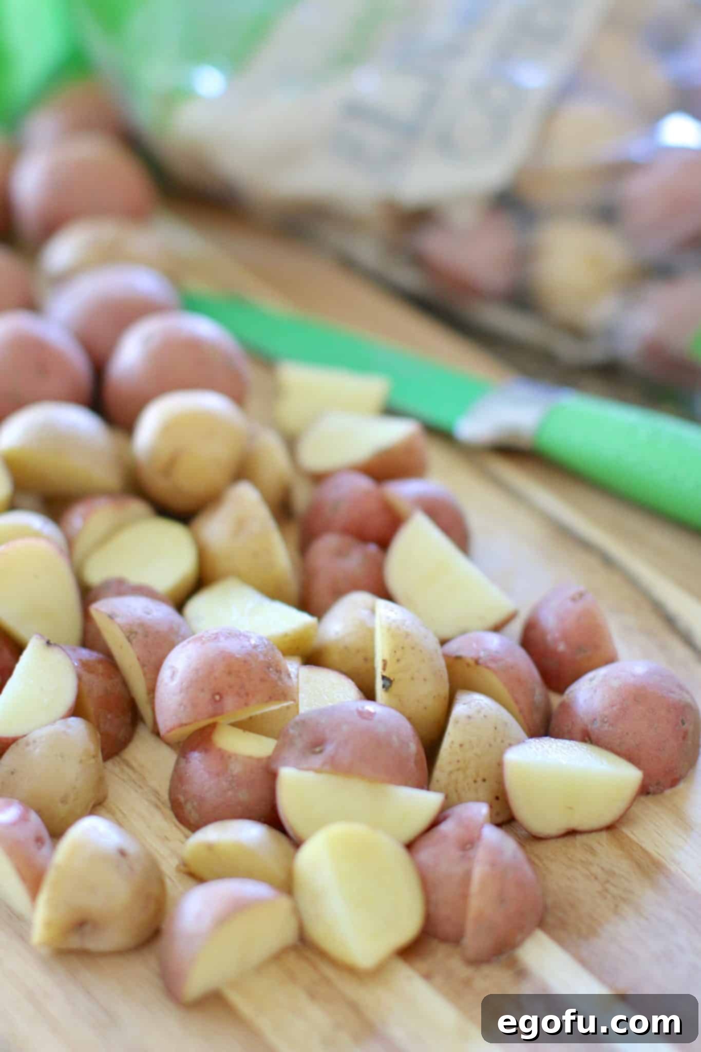 Little potatoes shown cut in half on a wooden cutting board.