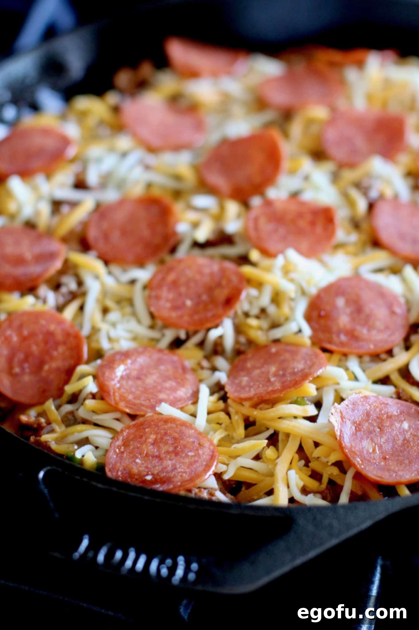Golden Skillet Cornbread Pizza 11 shredded cheese and sliced pepperoni slices on top of pizza in the skillet.