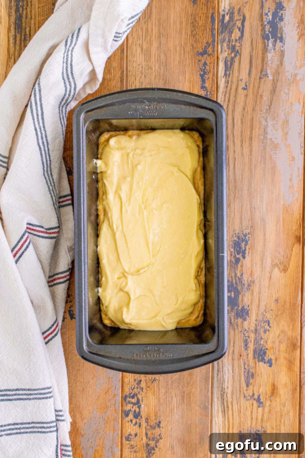 Cream Cheese Swirl Banana Bread 11 Cheesecake batter layered smoothly on top of the banana bread batter in a loaf pan, creating a distinct middle layer.
