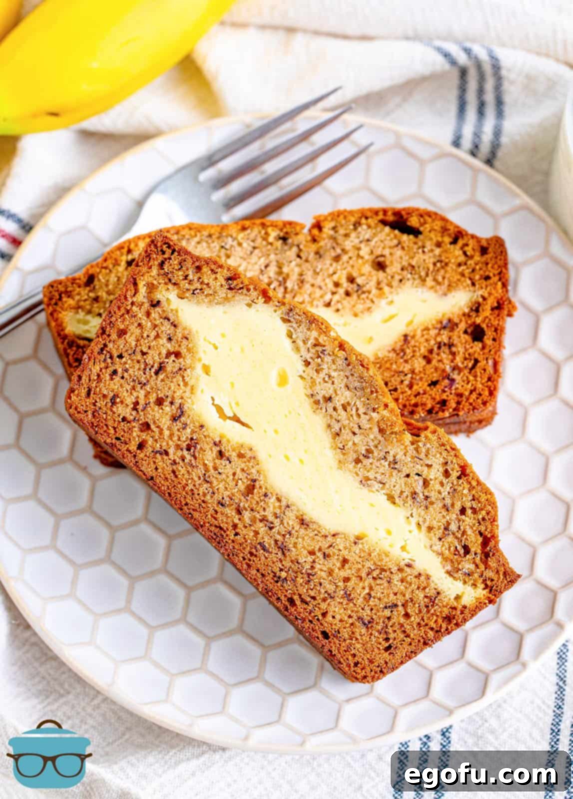 Cream Cheese Swirl Banana Bread 14 Two perfectly sliced pieces of cream cheese banana bread, stacked on a small white plate, ready to be enjoyed.