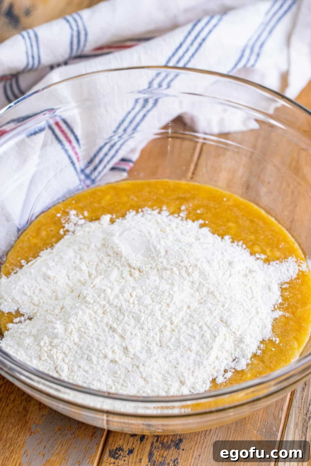 Cream Cheese Swirl Banana Bread 6 All-purpose flour being added to the mashed banana mixture in a bowl, ready to be gently mixed.