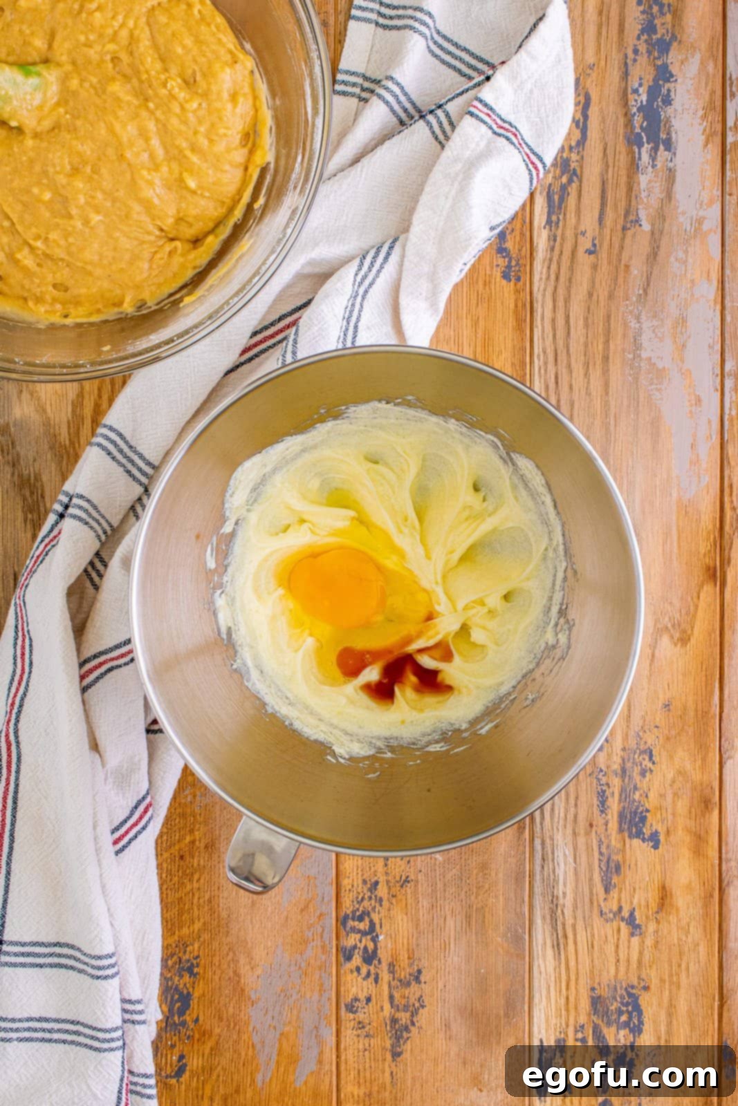 Cream Cheese Swirl Banana Bread 8 Egg and vanilla extract being added to the cheesecake mixture in a stand mixer, to be beaten until fully incorporated.