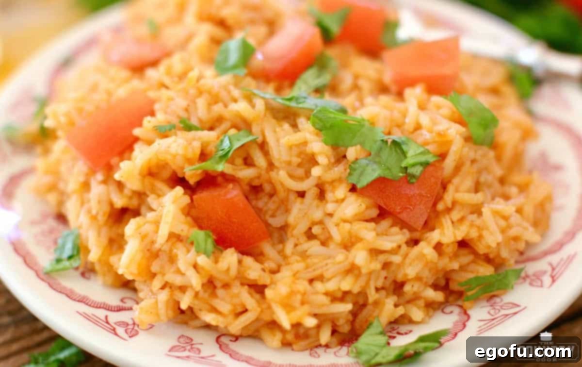 Mexican Rice shown on a plater and topped with diced tomatoes and chopped cilantro.