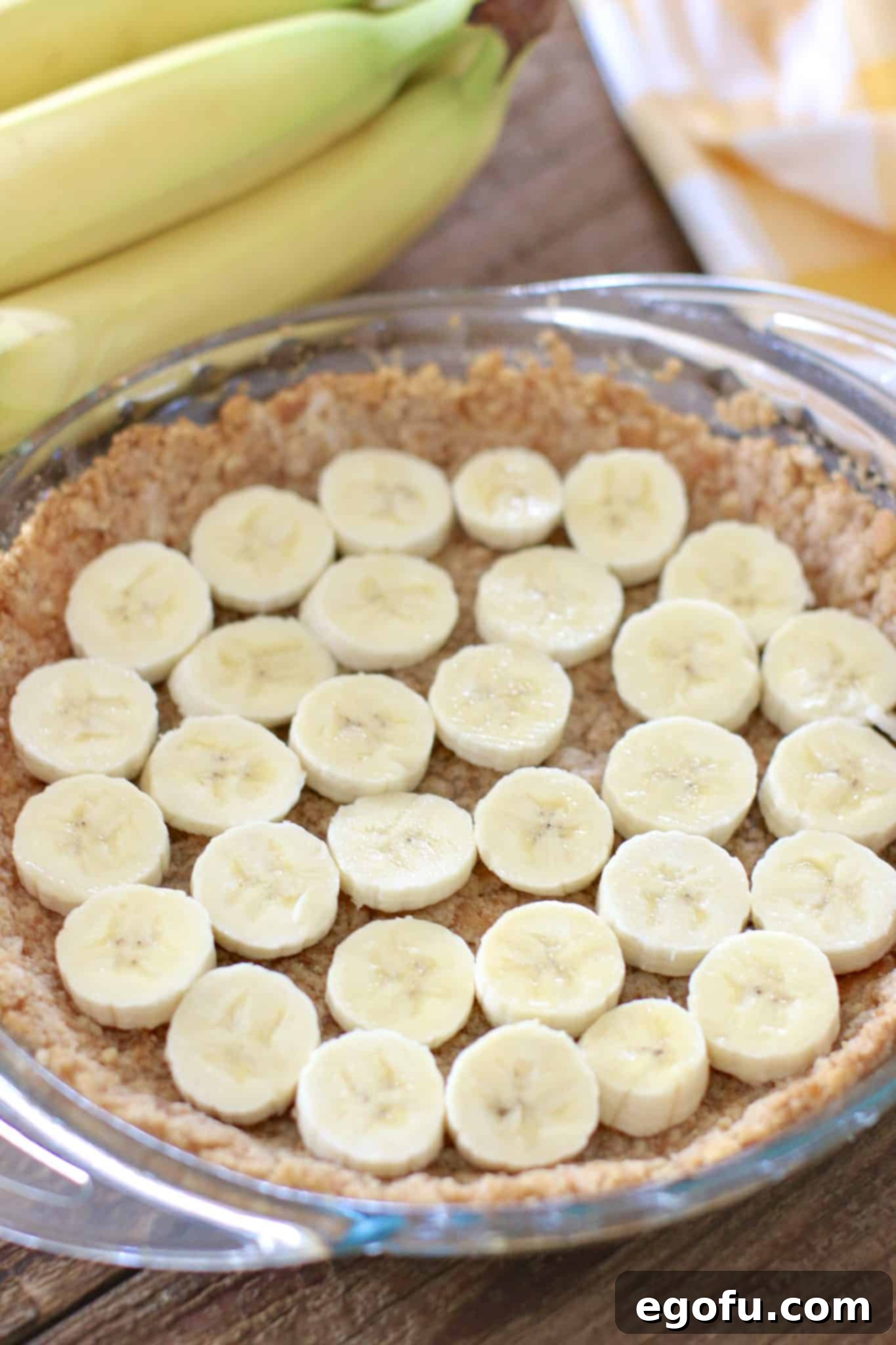 Sliced bananas layered perfectly on top of the cooled vanilla wafer crust, ready for the filling.