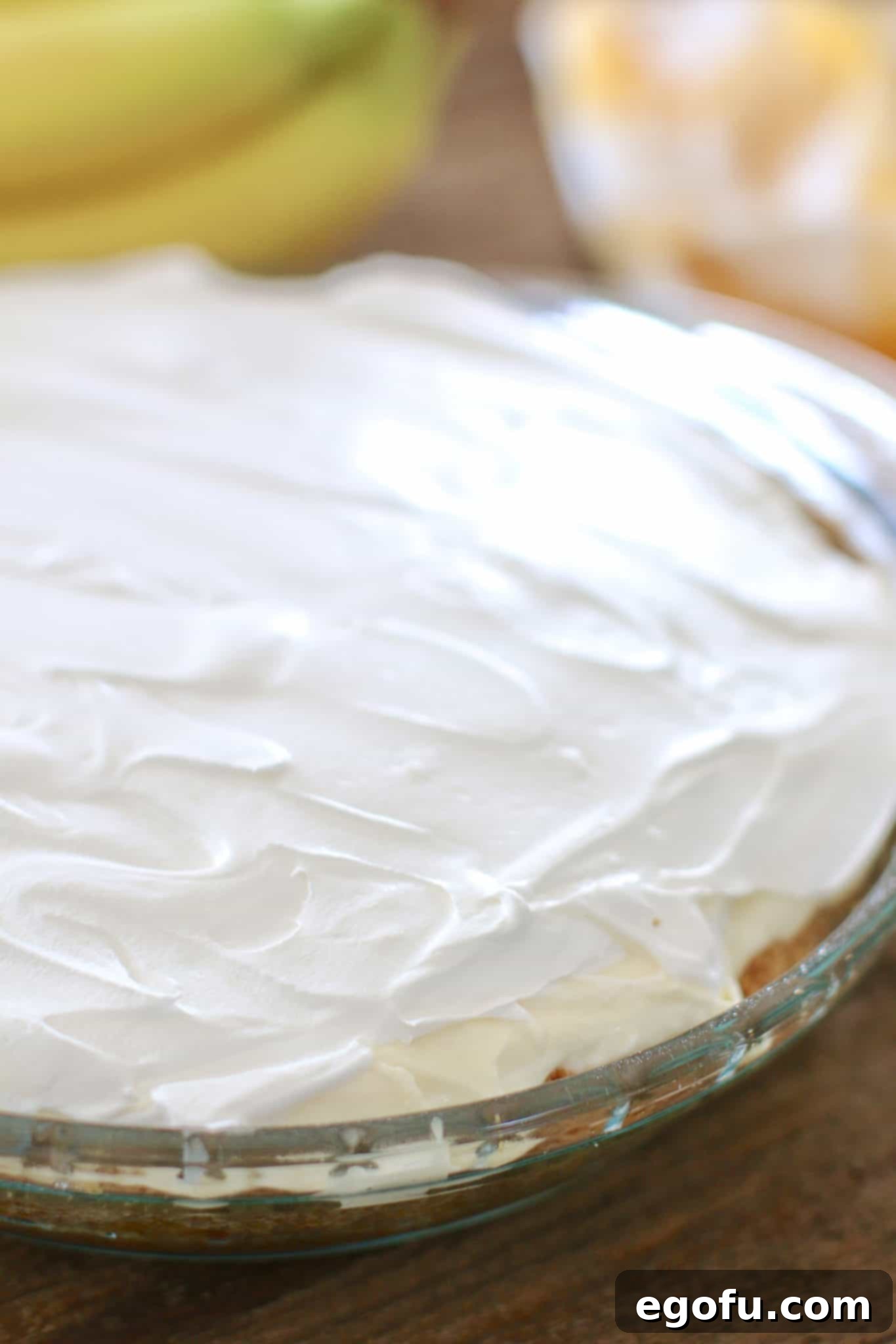 Cool Whip whipped topping spread smoothly over the banana cream pie filling, creating a perfect top layer.