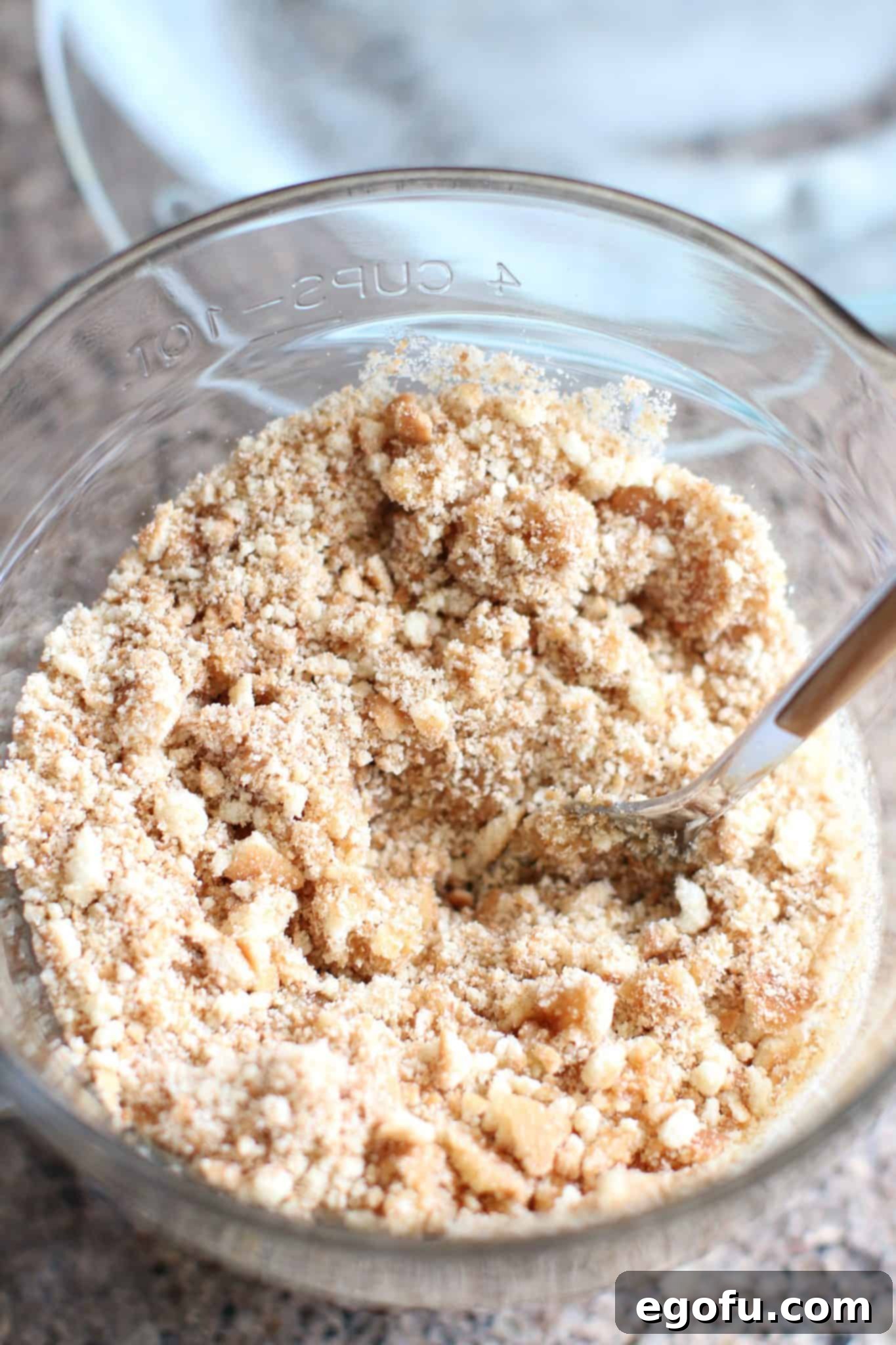 Melted butter stirred into crushed vanilla wafers and sugar in a bowl, forming the pie crust mixture.