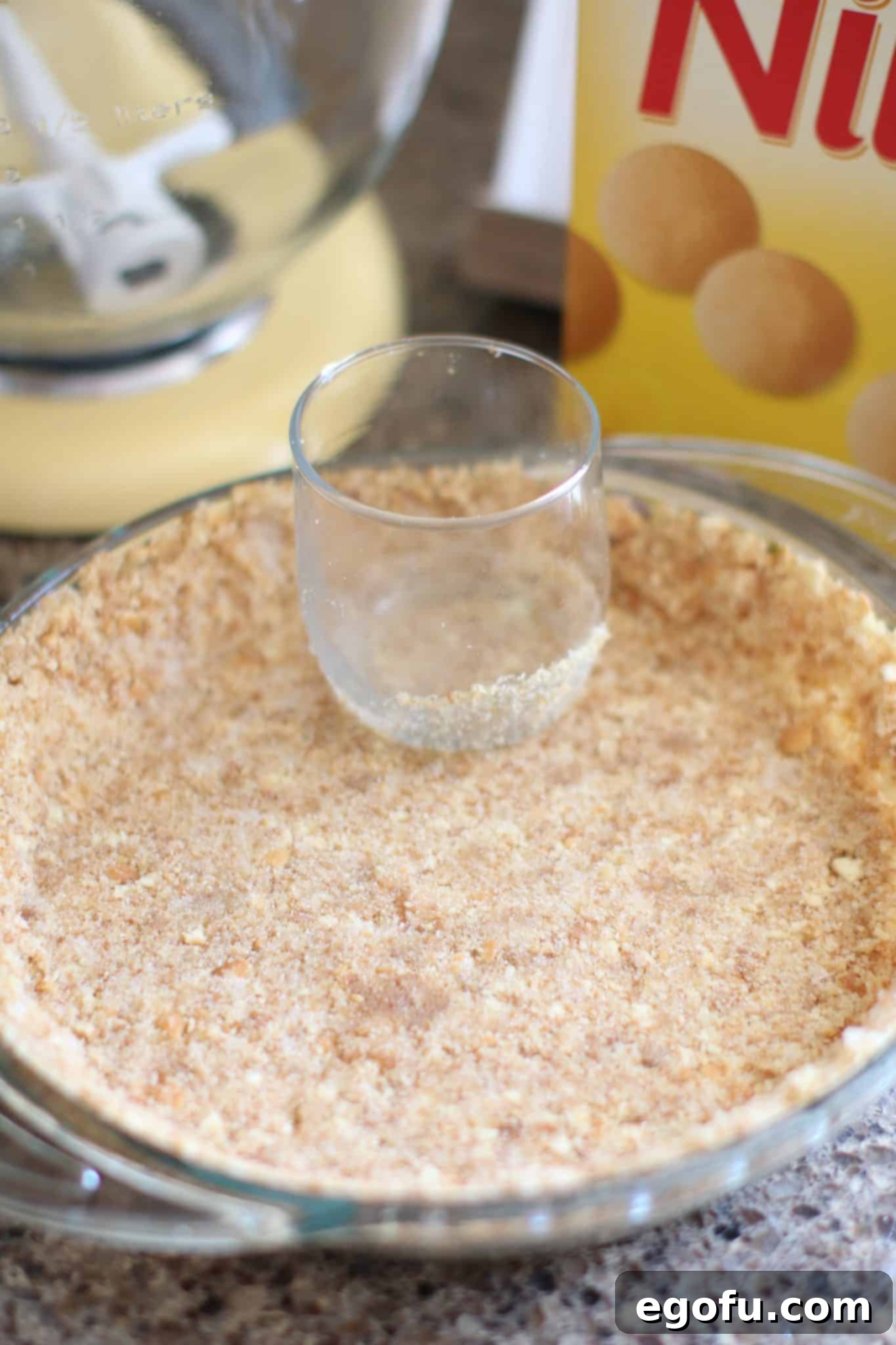 Pressing vanilla wafer crust mixture into a pie pan with a flat-bottomed glass to create a firm base.