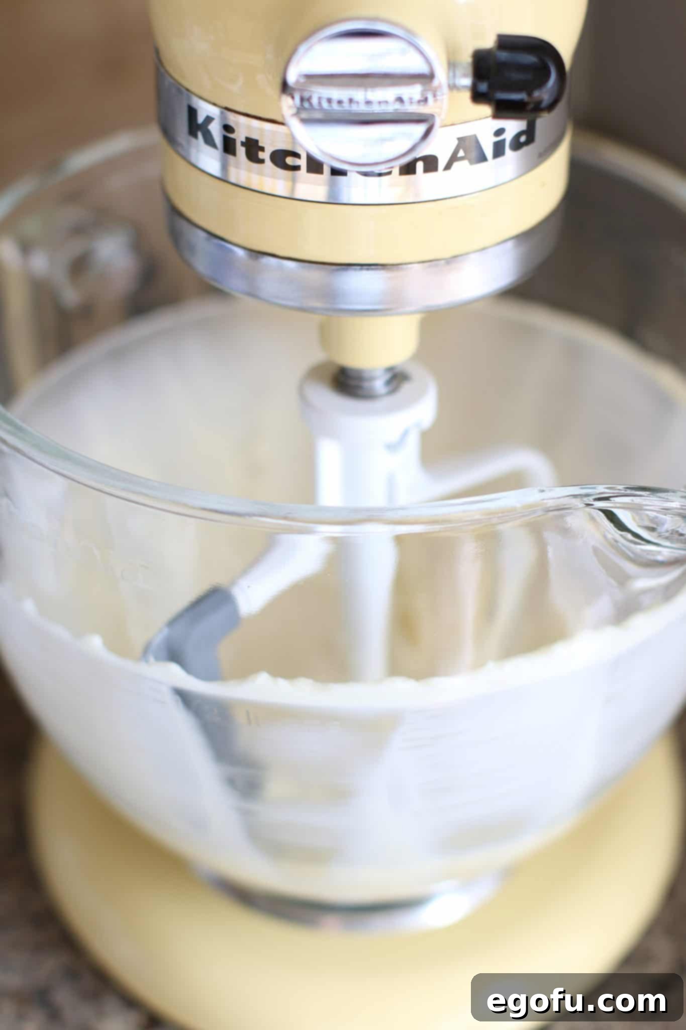Softened cream cheese and sugar being beaten until smooth and creamy in a stand mixer.