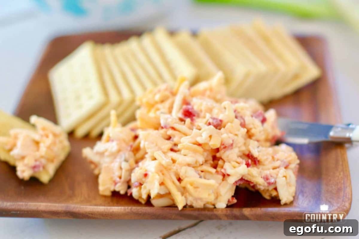 Classic Southern Pimento Cheese served on a rustic wooden board with a side of crisp club crackers, highlighting its rich texture and vibrant color.