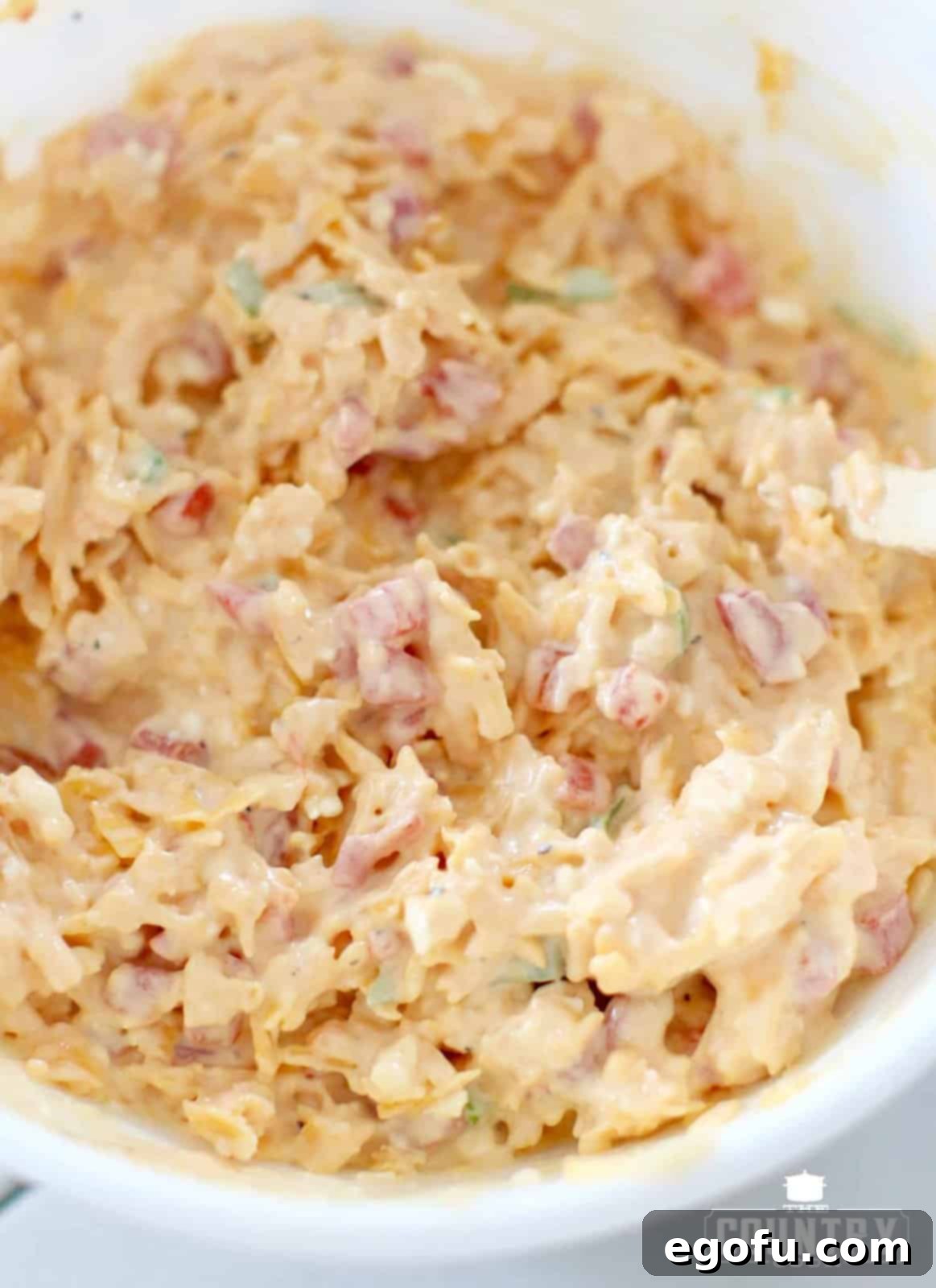 A close-up shot of the finished, perfectly chilled pimento cheese ready to be served in a rustic ceramic bowl, showcasing its creamy texture.