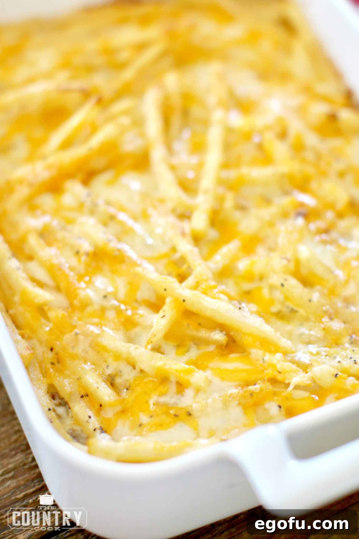 Cheeseburger and Fries Casserole shown fully cooked with melted cheese in a white baking dish.