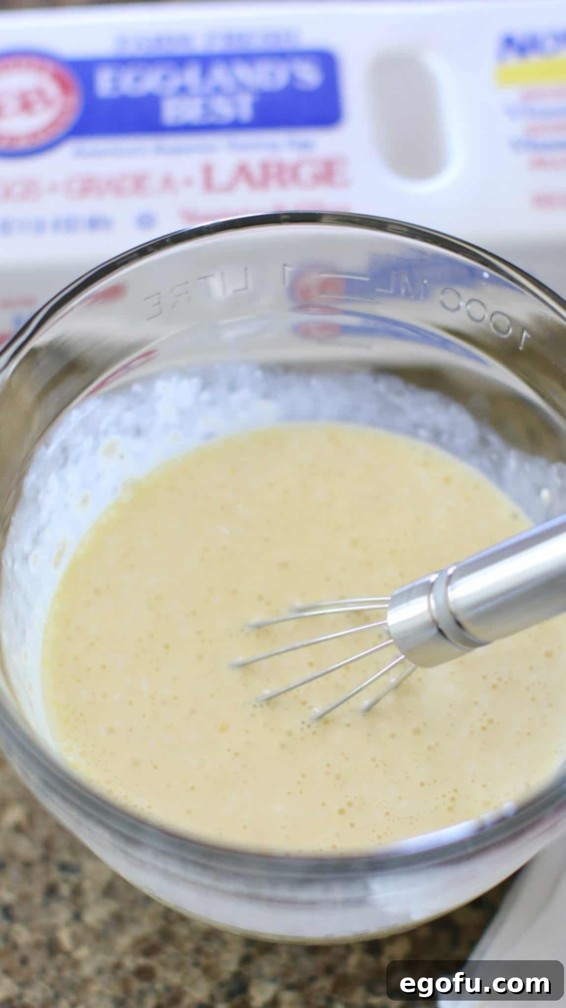 eggs and heavy creams beat together using a whisk in a glass bowl.