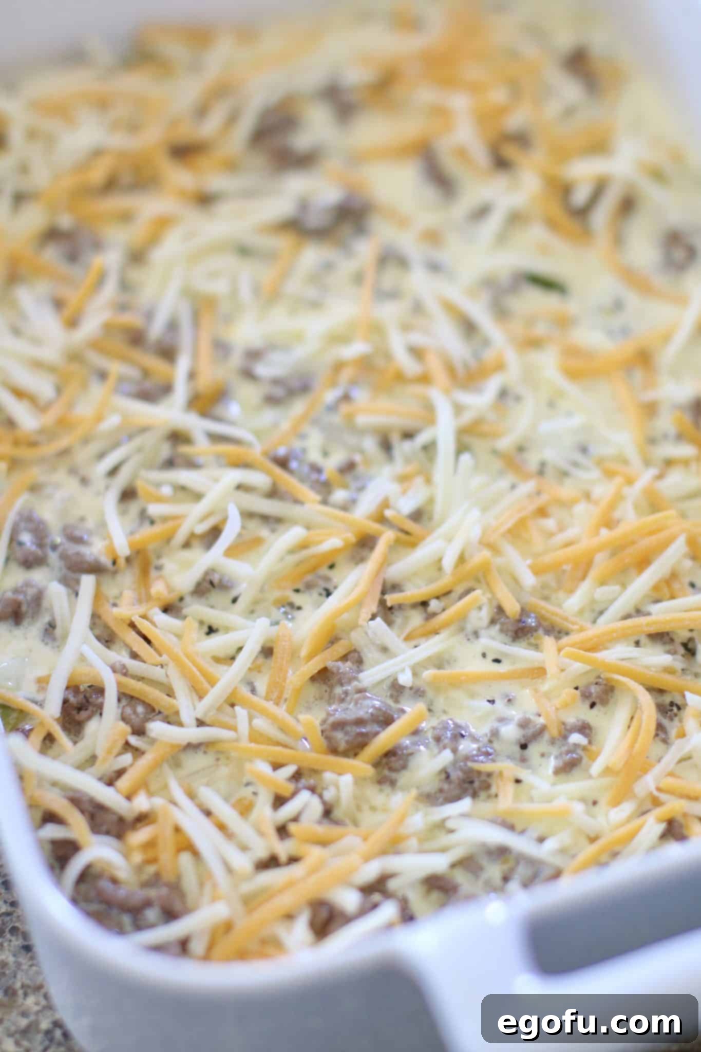 shredded cheese evenly sprinkled over ground beef mixture in baking dish.