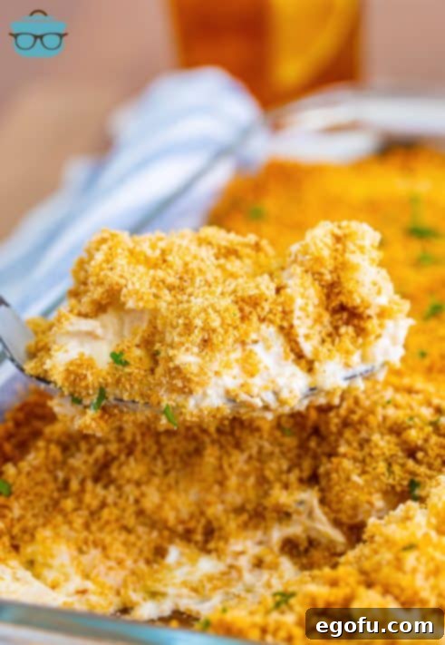 a large spoon scooping up some of the chicken and rice casserole out of the baking dish.