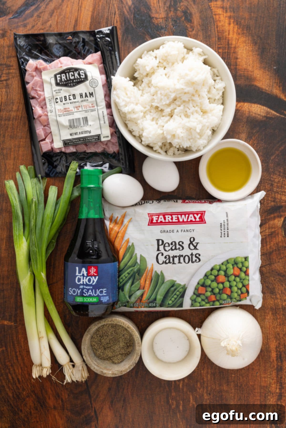 Golden Ham Fried Rice 5 A vibrant flat lay of all the essential ingredients for Ham Fried Rice: ham, rice, oil, eggs, soy sauce, green onions, salt, and pepper, meticulously arranged on a rustic wooden surface.