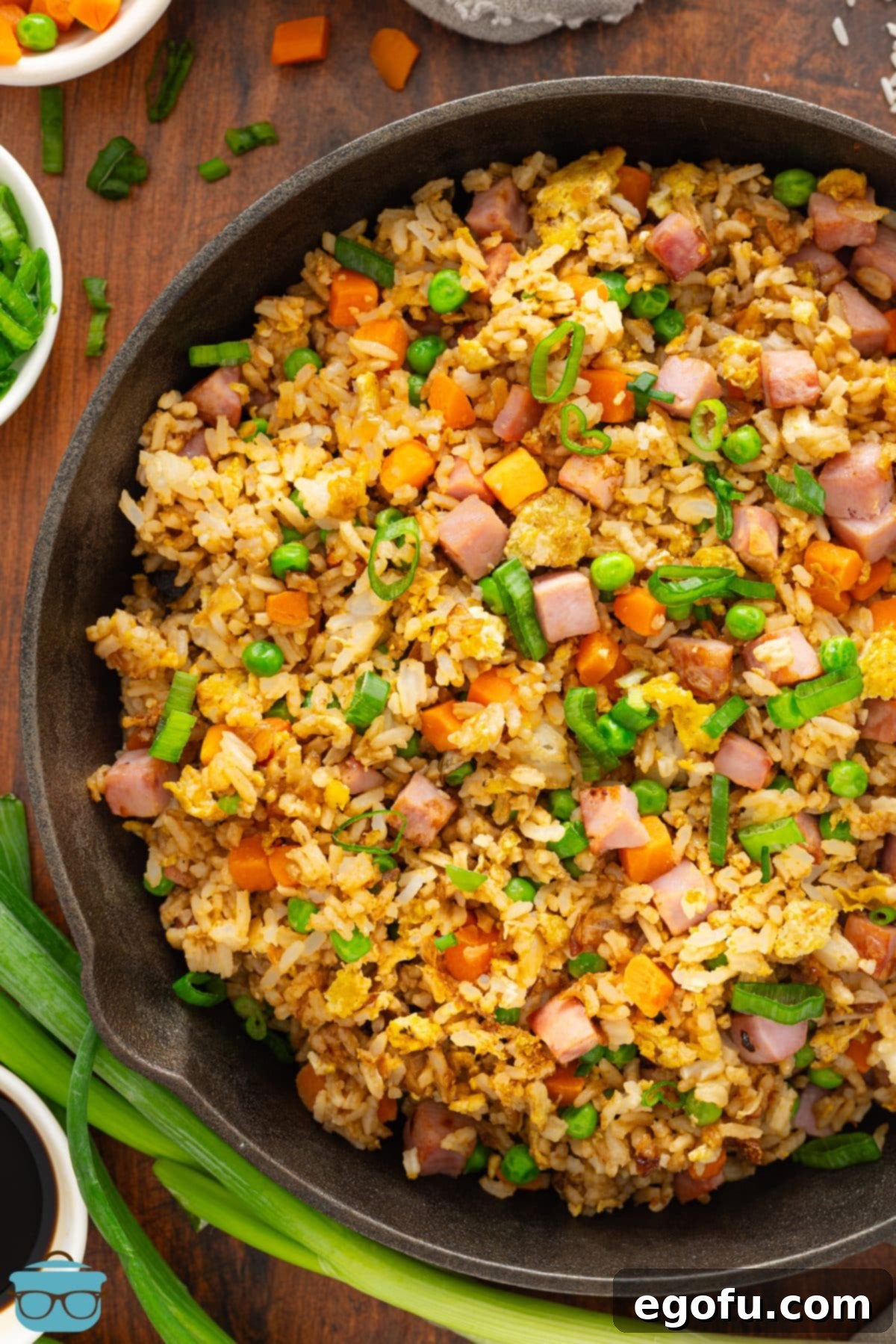 Golden Ham Fried Rice 7 A large skillet of freshly made Ham Fried Rice, garnished with vibrant green onions, ready to be dished out and enjoyed.
