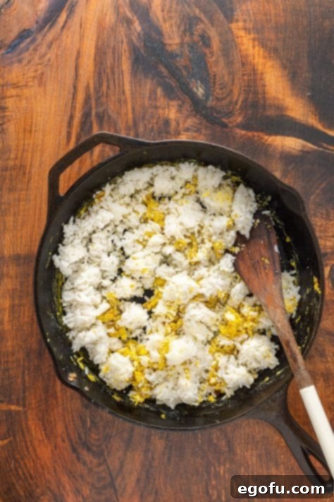 Golden Ham Fried Rice 10 Rice and eggs being mixed with ham and onions in a skillet, absorbing rich flavors for a perfect Ham Fried Rice.