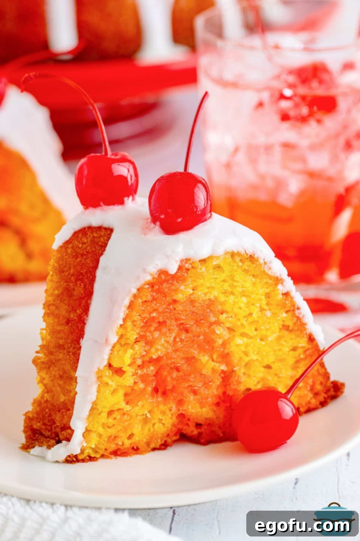 A vibrant slice of Shirley Temple Cake, topped with creamy frosting and a bright maraschino cherry, ready to be enjoyed.