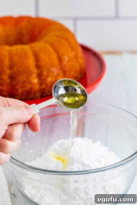Lemon extract being added to a bowl with icing ingredients.
