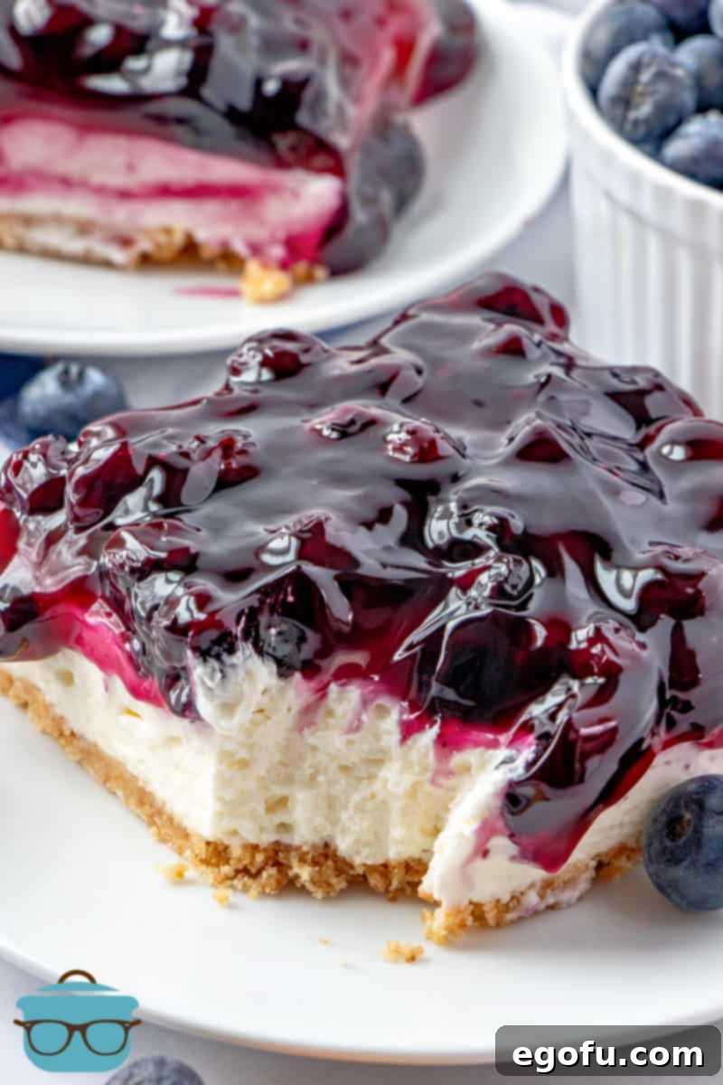 Grandma B's Blueberry Icebox Bars 12 close up photo of a slice of blueberry bars on a small white plate with a bite removed from the bar.