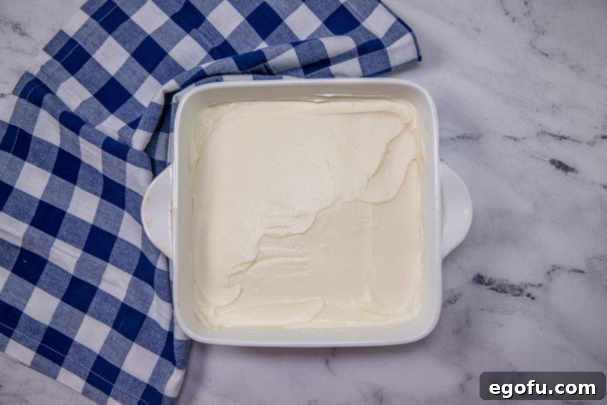 Grandma B's Blueberry Icebox Bars 9 sweetened cream cheese spread over vanilla wafer crust in white square baking dish.