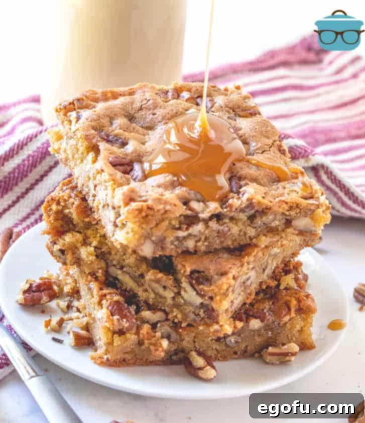 pecan cake bars stacked three on a small white plate with caramel sauce drizzling on top