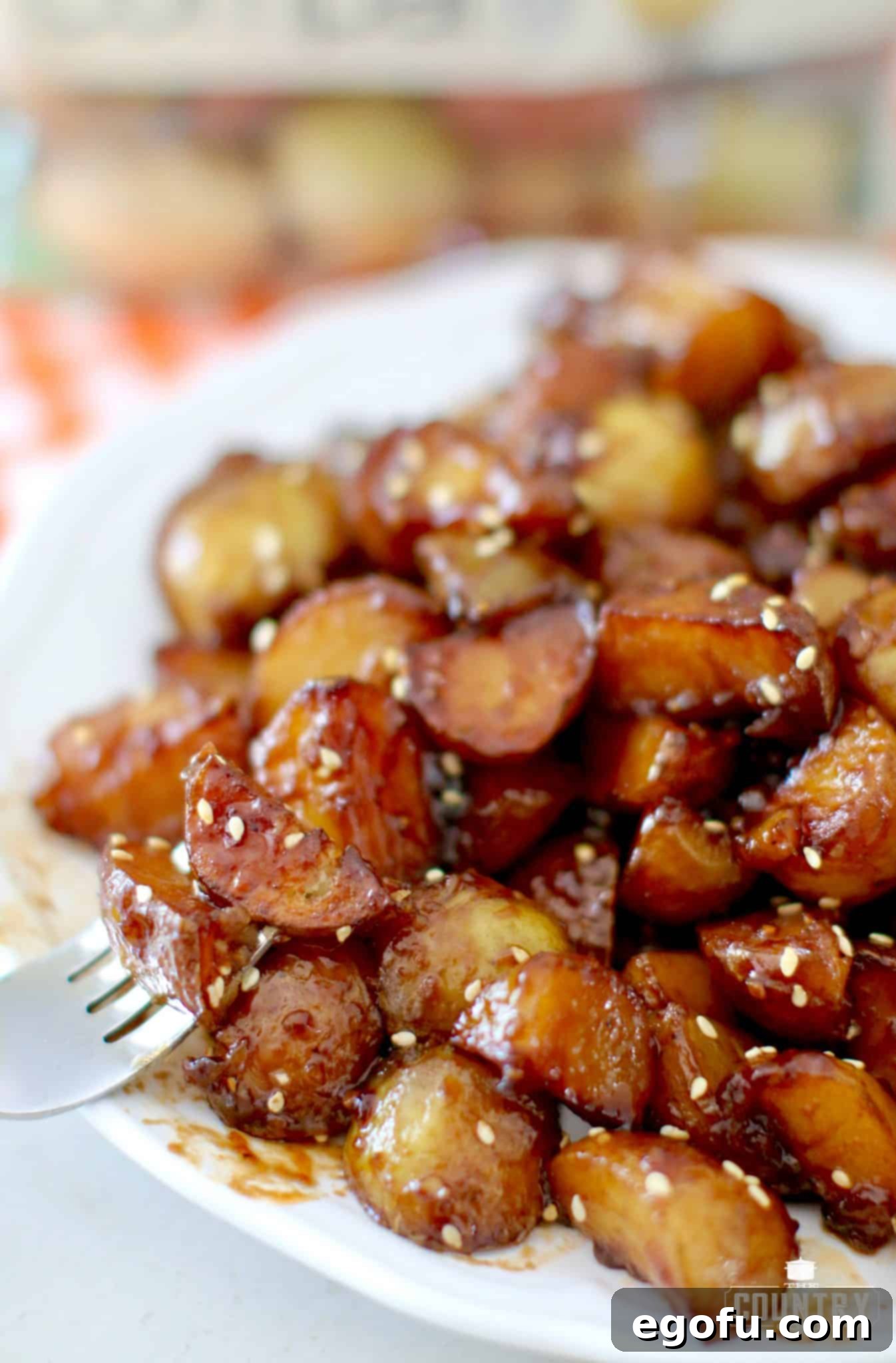 a fork holding up a serving of sticky potatoes on a white plate.