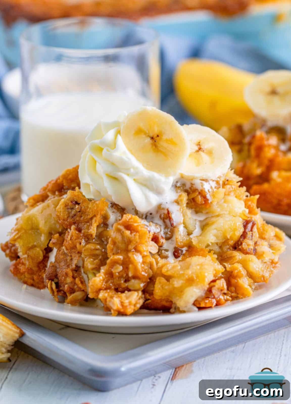 A delightful serving of Southern Banana Cobbler on a white plate, beautifully topped with a scoop of vanilla ice cream and garnished with fresh banana slices, showcasing its irresistible appeal.