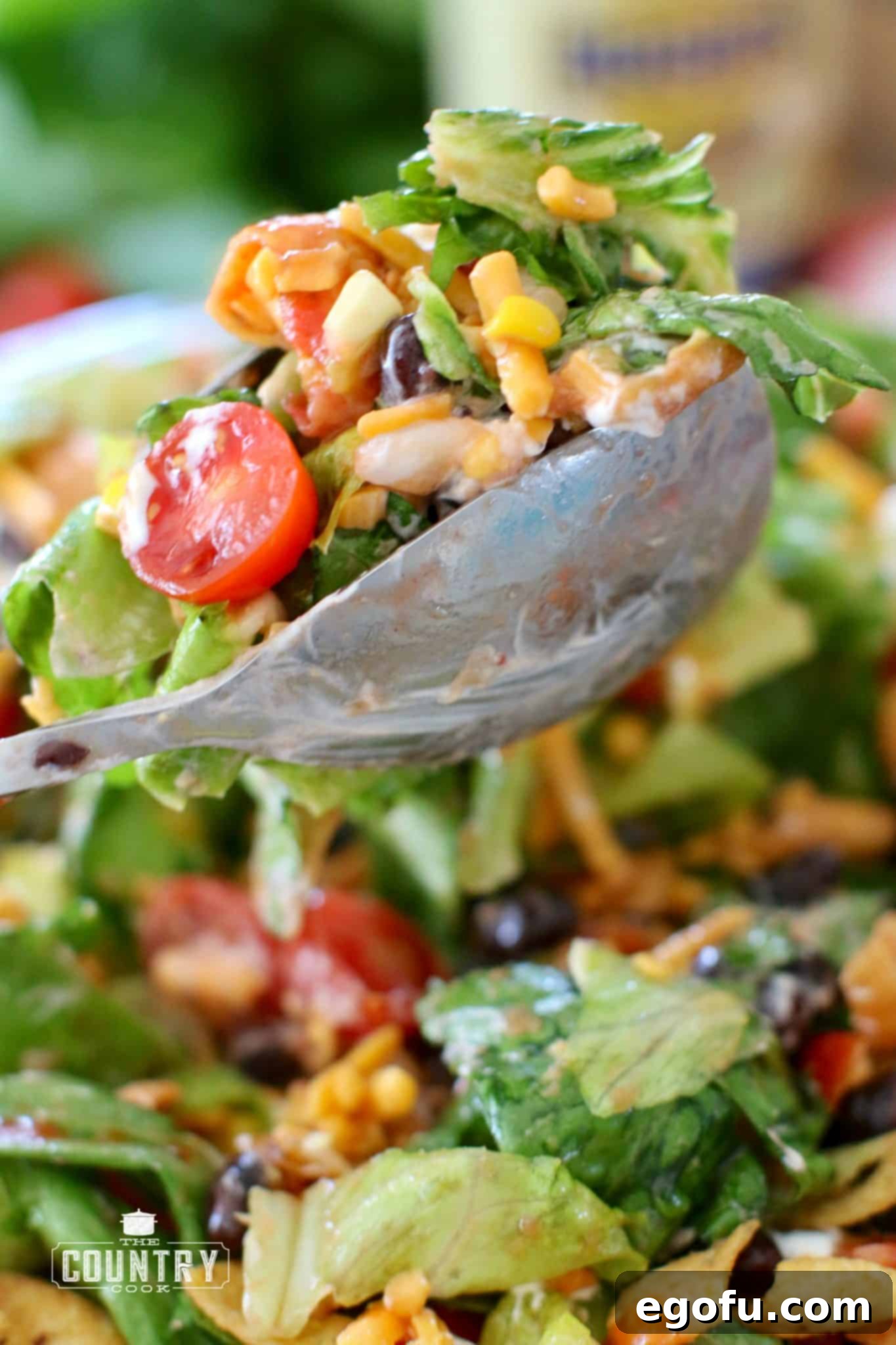 Frito Fiesta Taco Salad 7 Vegetarian Taco Salad being scooped with salad tongs from a large bowl, ready for plating.