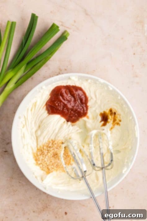 Lemon juice, Worcestershire sauce, minced onion, and chili sauce being added to mayo and cream cheese mixture.