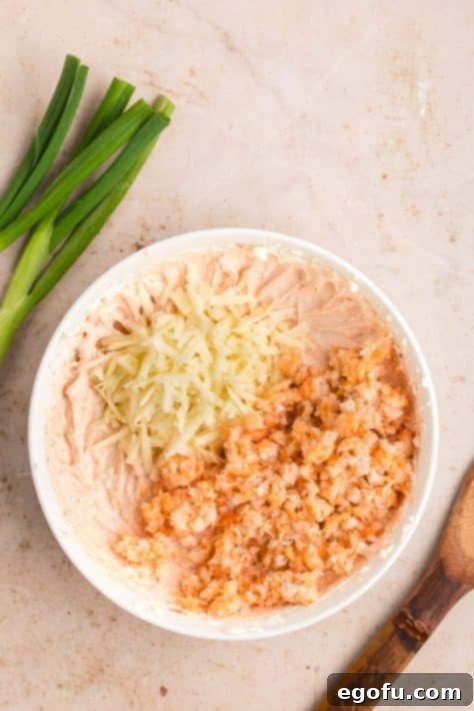 Cheese and shrimp being added to a creamy dip.