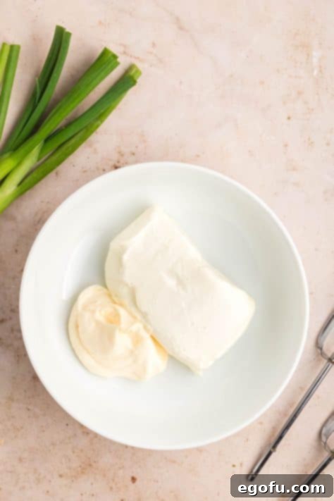 Cream cheese and mayo being beaten together in a bowl.
