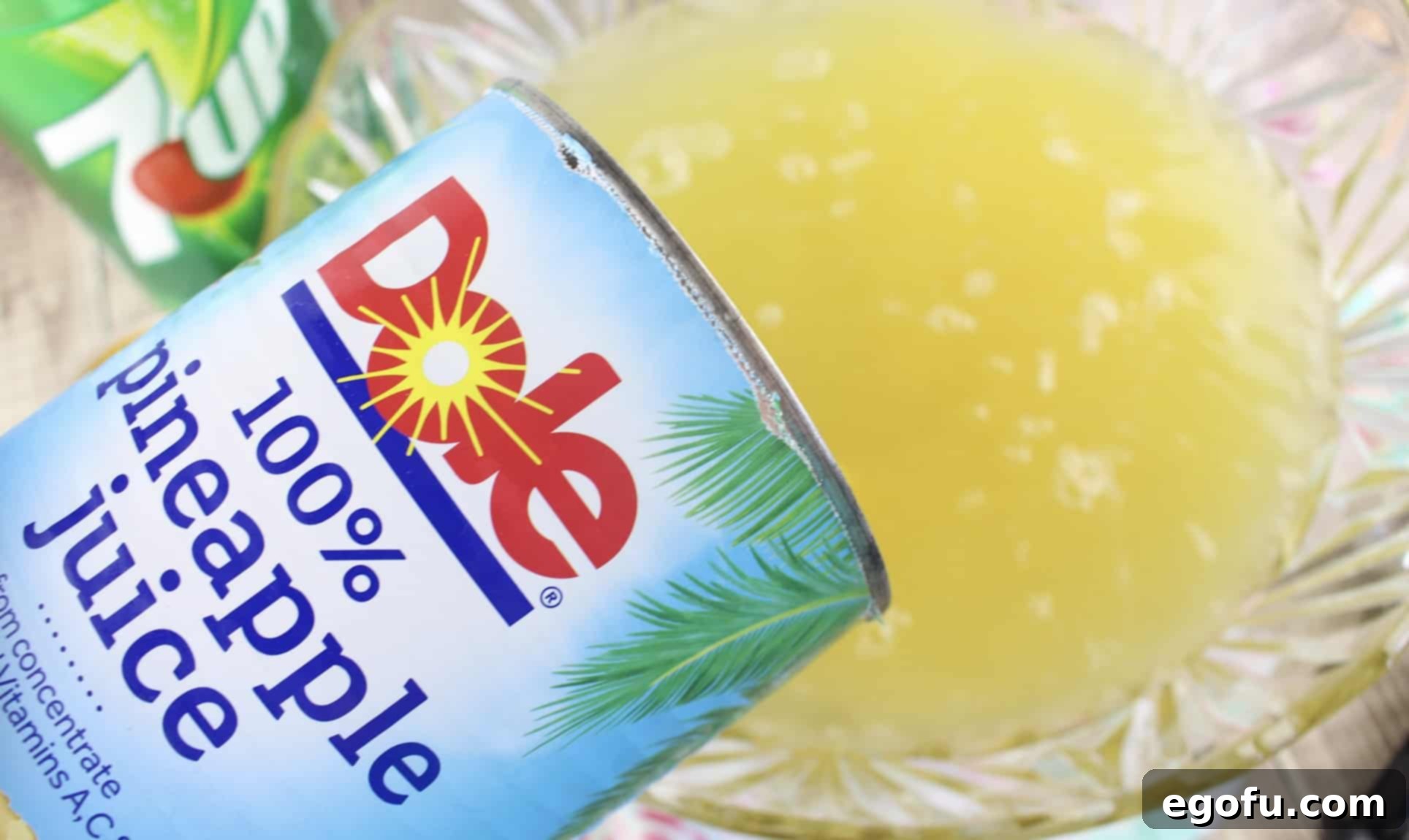 Pouring pineapple juice into a large punch bowl, mixing with other ingredients.