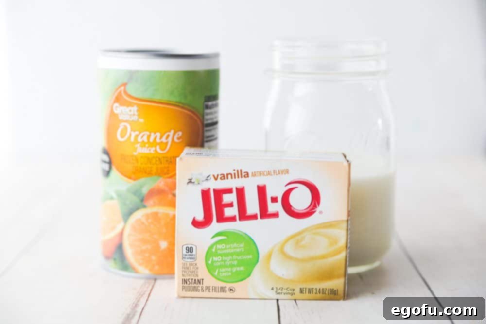 Close-up view of the key ingredients for Orange Creamsicle Salad laid out: mandarin oranges, pineapple, bananas, and a packet of pudding mix.