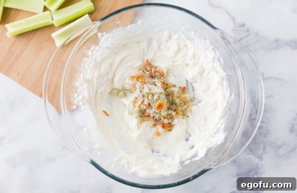 Cream cheese and vegetable soup mix in a clear bowl, ready to be combined into a savory filling.