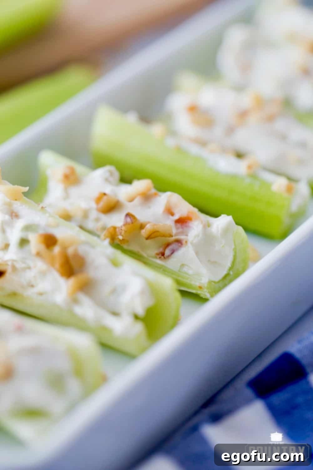 Closeup photo of celery stuffed with cream cheese and topped with chopped walnuts.
