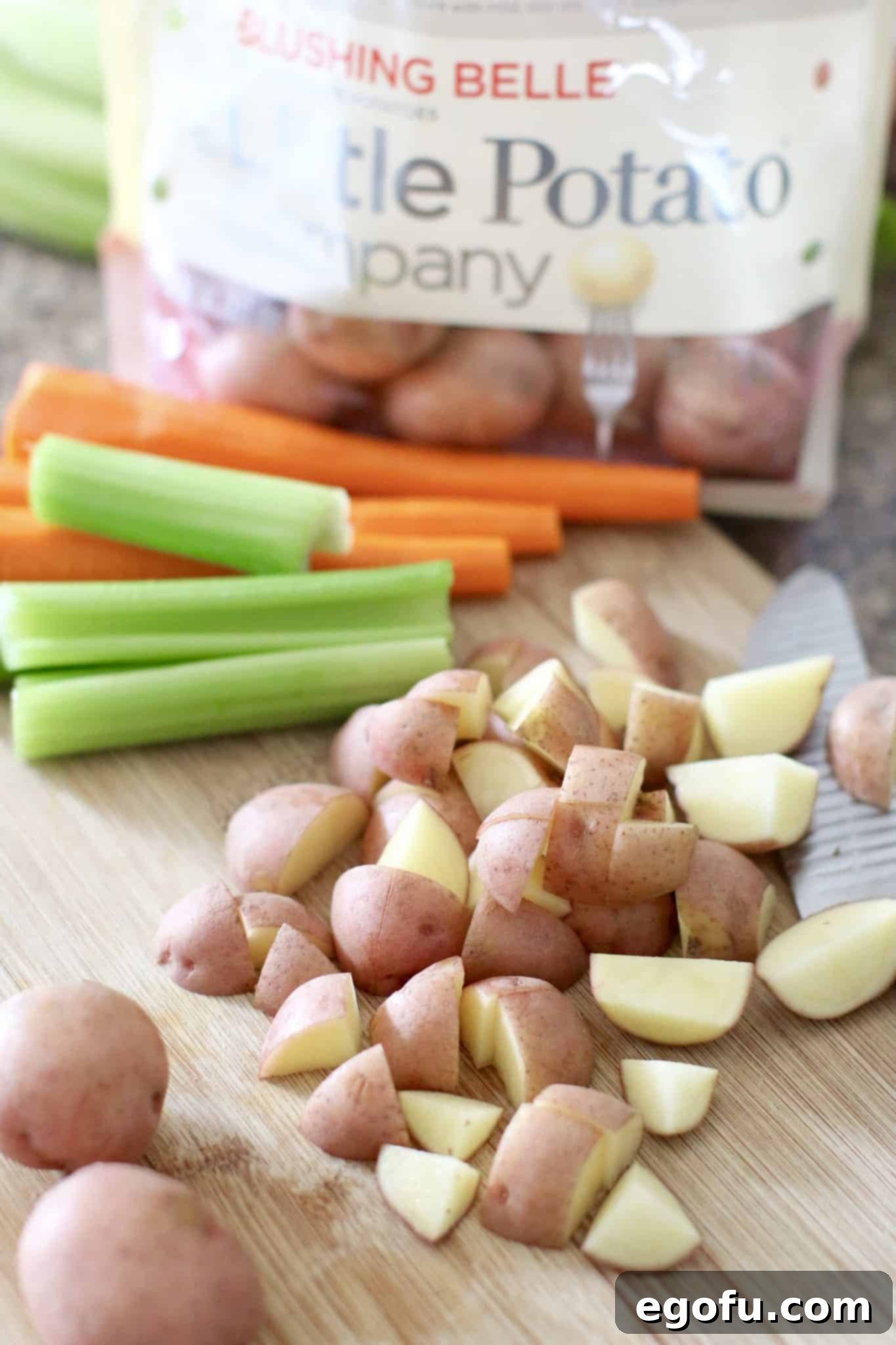 chopped potatoes, celery and carrots on a wooden cutting board.