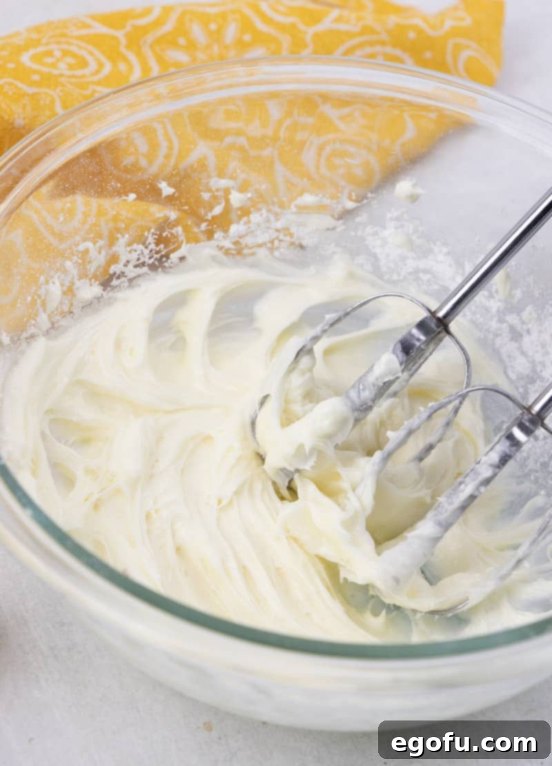 Making cream cheese frosting using an electric mixer in a glass bowl for the glaze