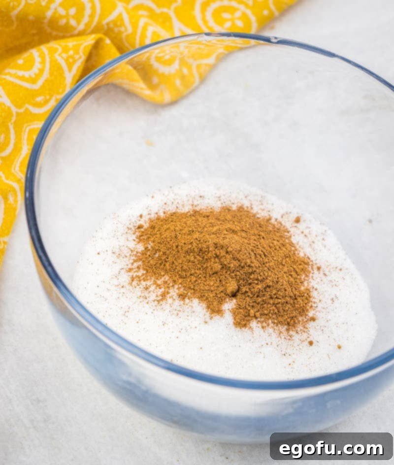 Mixing sugar and pumpkin pie spice together in a glass bowl for coating