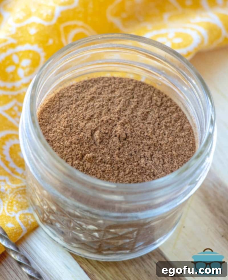 Homemade Pumpkin Pie Spice mixed together in a mason jar shown on a wood surface.