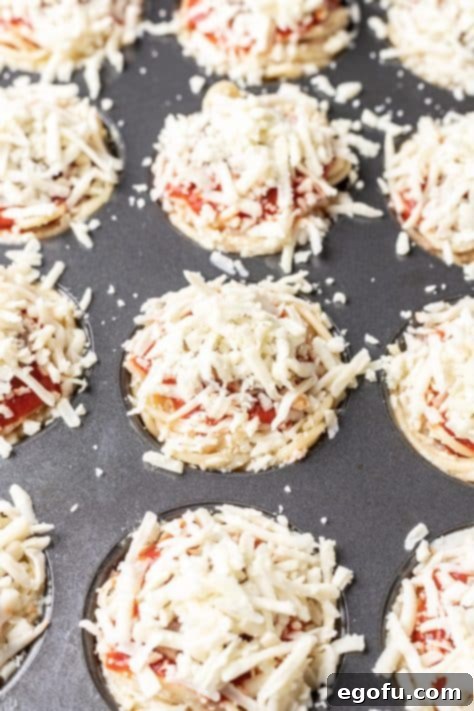 Mozzarella cheese, sausage, sauce, and pasta in muffin tins.