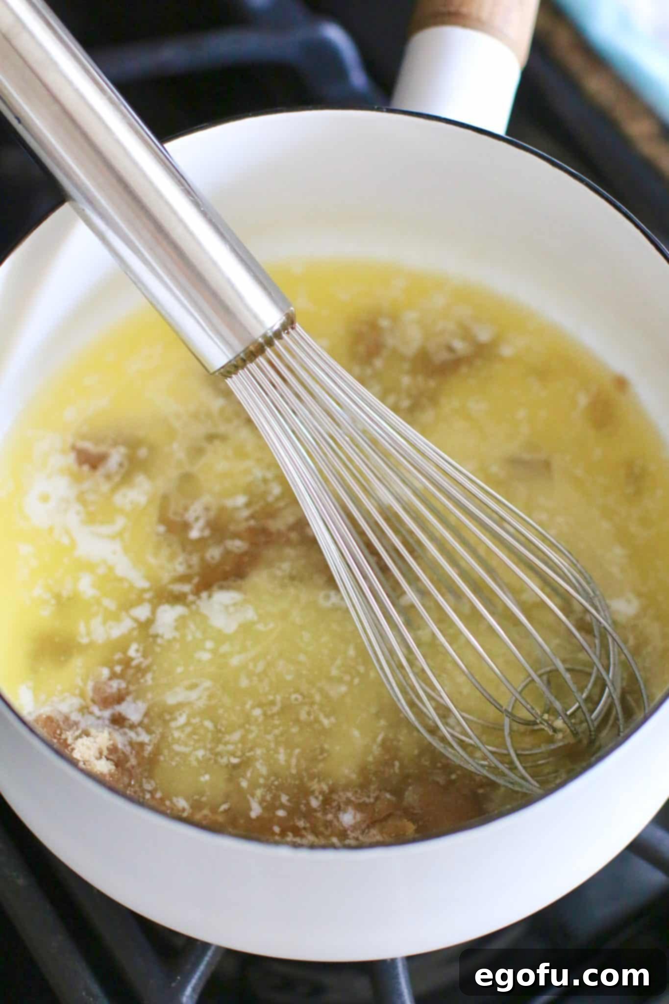 brown sugar, butter, milk being whisked together in a white pot. 